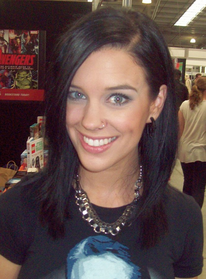 Stephanie Bendixsen from TV's Good Game voices Vet Corgi. Here she is pictures at a fan convention with long straight black hair and a black t-shirt.